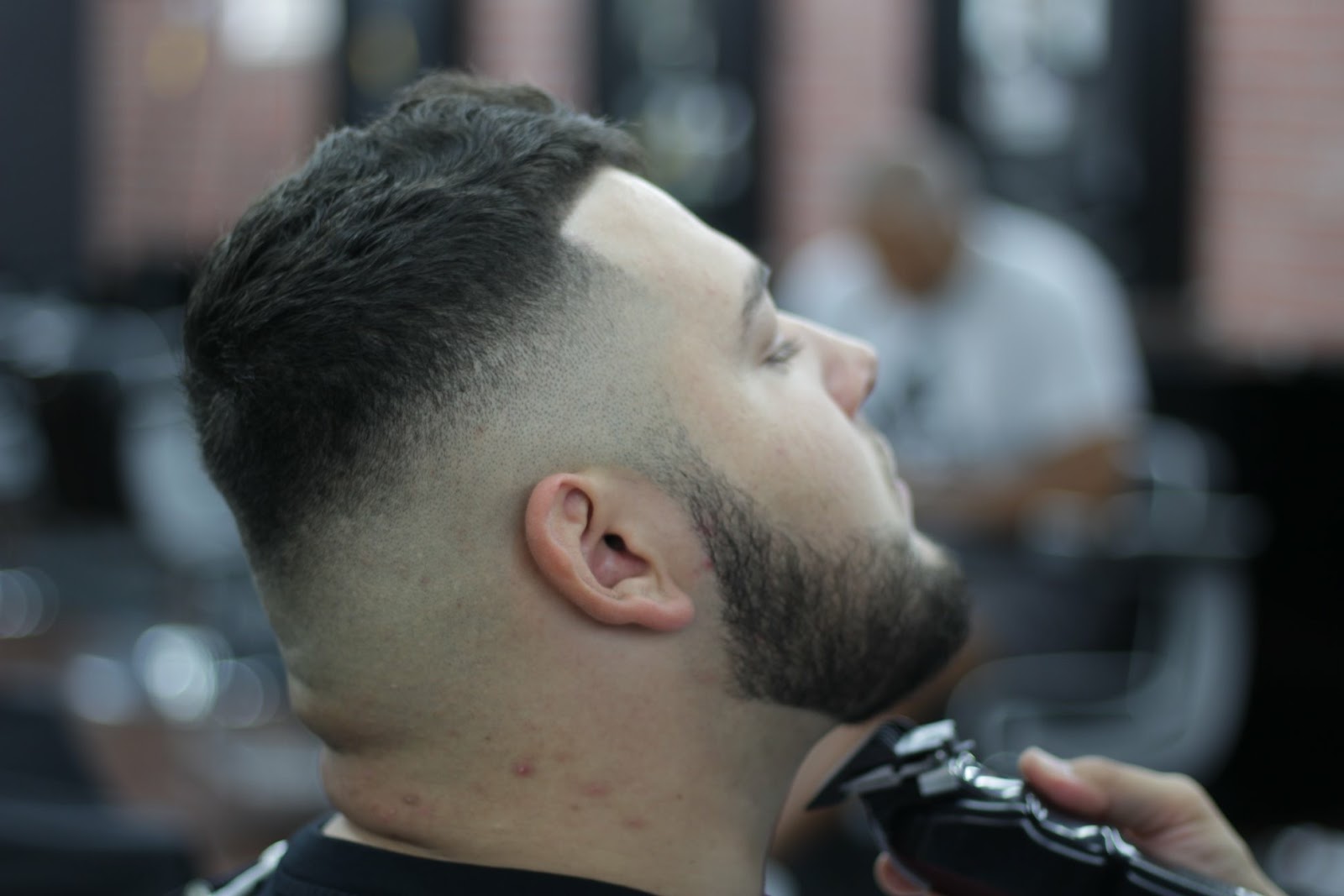 Mid fade blended tight with the beard lined at the jaw, clippers still at the neck
