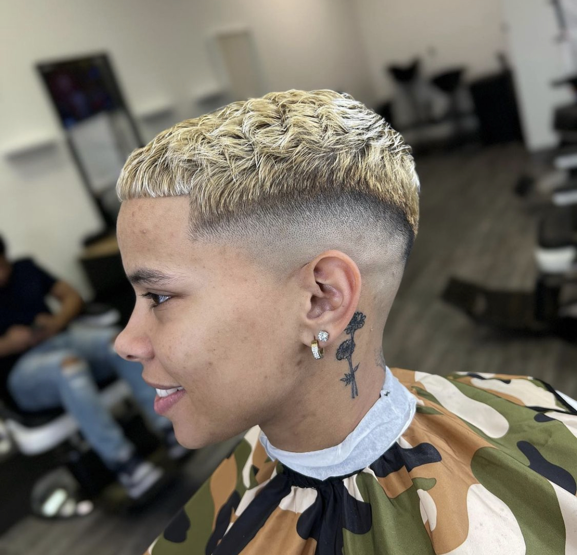 Drop fade under a cropped blonde top, client smiling in the chair